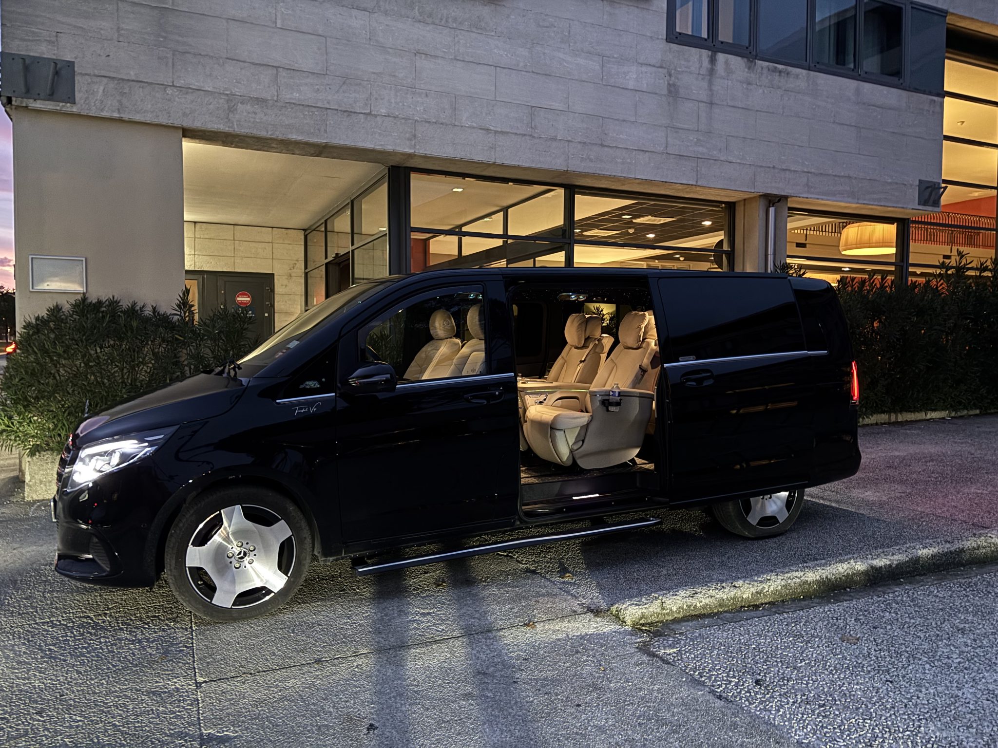 Mercedes Classe VIP noire avec chauffeur privé devant l'hôtel, transfert vers les stations de ski